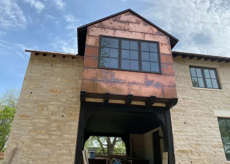 Copper metal panel facade on a stone building for Roof Repair in Springville