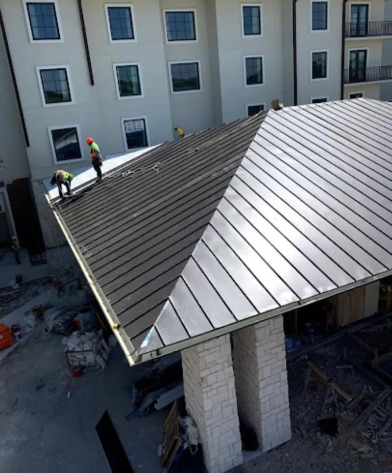 Crew installing standing seam metal roof panels on a commercial project in Springville